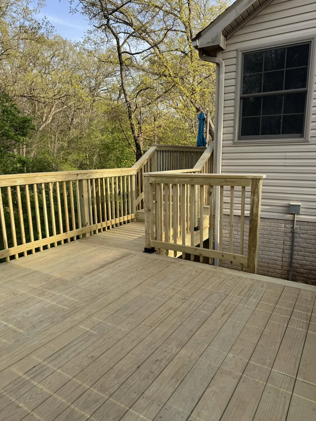 Rebuilt corner deck with new wood railing in Pekin, Illinois